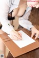 A woman sitting at a desk writing on a piece of paper.