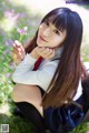 A young woman sitting on the ground holding a flower.