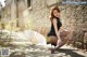 A woman in a black dress sitting on the ground with a white umbrella.