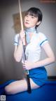 A woman in a blue and white uniform holding a pool cue.