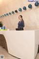 A woman standing behind a white reception desk.