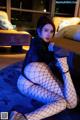 A woman in fishnet stockings sitting on a bed.