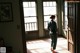 A woman standing in a room looking out of a window.