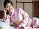 A woman in a pink kimono laying on a bed.