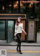 A woman walking down the street in front of a restaurant.