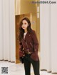 a woman standing in front of an elevator wearing a maroon jacket