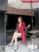 A woman sitting on a chair under an umbrella.