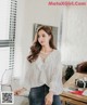 a woman sitting on a couch wearing a white blouse and jeans