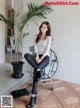 A woman sitting on a chair next to a plant.