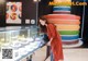 A woman standing in front of a display case filled with cakes.