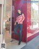 A woman leaning against a red wall in a store.