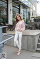 A woman wearing white jeans and a pink sweater.