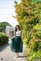 A woman in a white top and green pleated skirt.