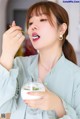 A woman eating a glass of milk with a spoon.