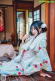 A woman in a kimono sitting on a wooden floor.