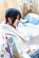 A woman in a kimono sitting on a bed.