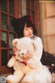 A girl sitting on a window sill holding a teddy bear.