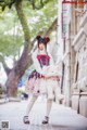 A girl in a dress holding a teddy bear on a sidewalk.