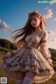 A woman in a dress with a cat ears headband standing in a field.