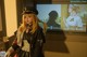 A woman dressed in a police uniform standing in front of a television.