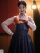 A woman in a korean dress standing in front of a red wall.