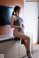 A woman sitting on top of a kitchen counter next to a television.