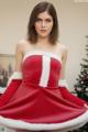 A woman in a red and white dress posing in front of a Christmas tree.