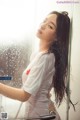 A woman in a white shirt is standing in a shower.