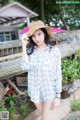 A woman wearing a straw hat standing next to a wooden fence.