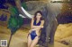 A woman in a blue bikini standing next to an elephant.