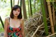 A woman in a floral dress standing in front of a bamboo structure.