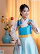 A woman in a blue and white hanbok poses for a picture.