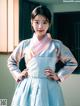 A woman in a blue and pink hanbok posing for a picture.