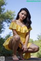 A woman in a yellow dress crouching down on the ground.