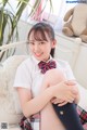 A young woman sitting on a bed with a teddy bear.