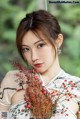 A woman in a chinese dress holding a bunch of flowers.