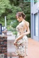 A woman in a white dress standing on a brick wall.