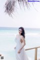 A woman in a white dress standing on a beach.