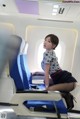 A woman sitting on a blue chair in an airplane.