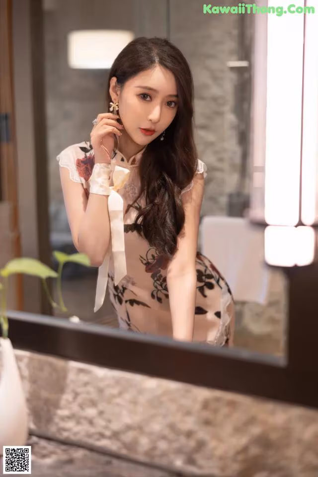 A woman in a cheongsam sitting in front of a mirror.