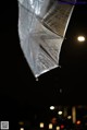 A silver umbrella hanging from a string in the rain.